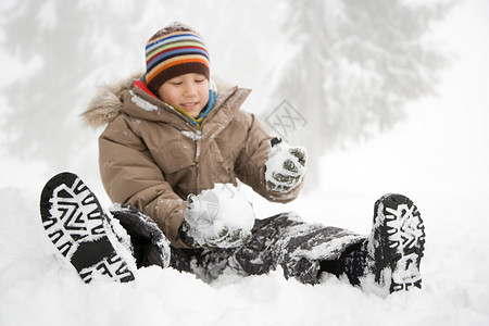 坐在雪地里的男孩图片