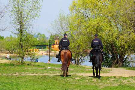 两名骑马的警察在堤岸巡逻人们正在水边休图片
