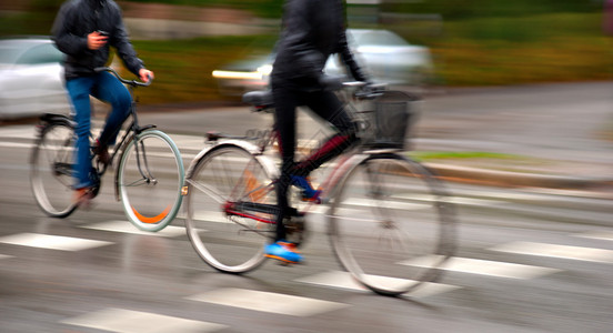 两个人下雨天在潮湿的街道上骑自行车背景图片