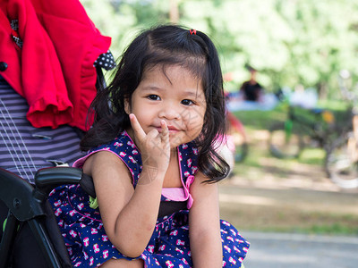 坐在公共园的婴儿车里的小亚洲女孩图片