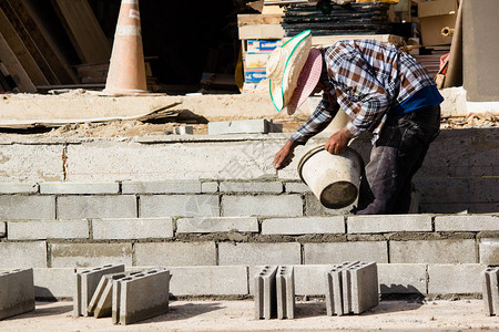 泥工或砖建造者在建筑工地建造水泥砖墙工人们正在建造筑物图片
