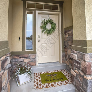 方形框架带有白色木质前门侧灯和横梁窗的住宅入口入口处装饰着花圈盆栽开图片
