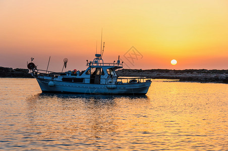 一艘渔船在峡湾的日落时分图片