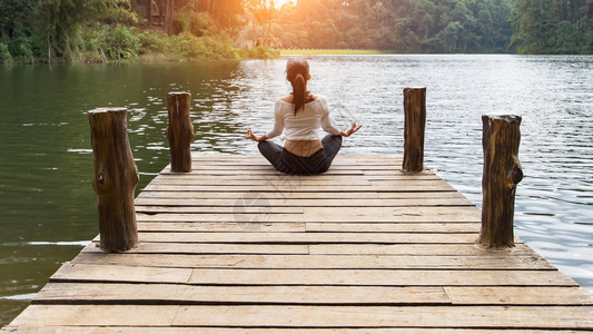 年轻健康女子在桥上做瑜伽在自然舒适放松生图片