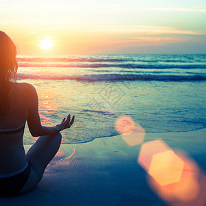日落时分在海边练习瑜伽的白种女人图片