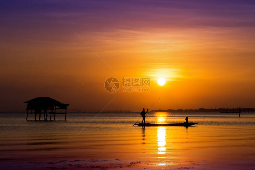 在湖边有日落的天空的渔船上最小渔民图片