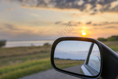 驾驶汽车的后视镜映出夕阳景观图片