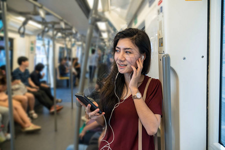 在Skytratrain铁路上使用和监听音乐智能手机的临时穿便衣图片