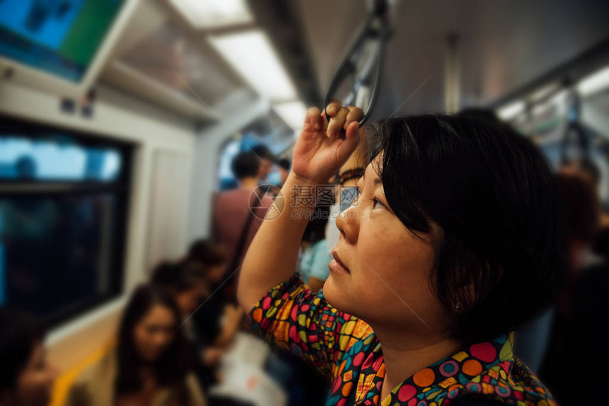 亚洲女人在城市的轻轨列车上旅行城市里的许多人使用轻图片