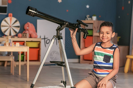 带望远镜的非裔美国小男孩晚上看星在图片