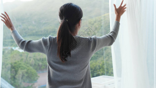 女人在家揭开窗帘图片