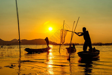 渔民使用渔网在日落时在湖边捕图片