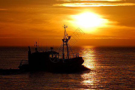日落时离开港口的领航船剪影图片
