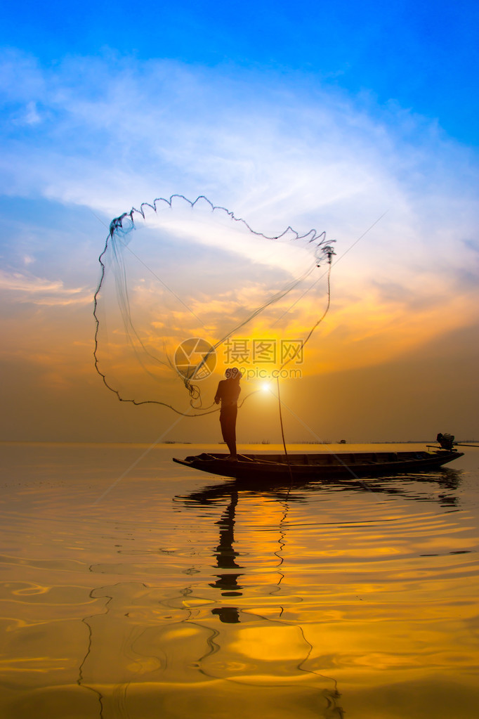 在泰国日落时丢渔网的鱼人休威特Silhou图片
