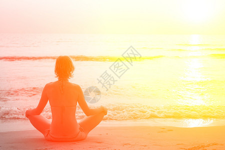 坐在沙滩上练瑜伽的女人的瑜伽女图片