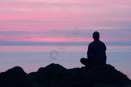 一个人坐在海边的岩石上图片