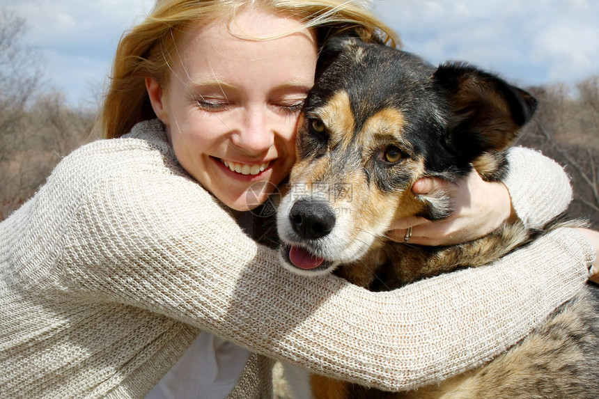 一个拥抱她德国牧羊犬的快乐女人可爱而图片