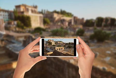 一位游客正在用手机拍下没有人被夕阳照亮的罗马广图片