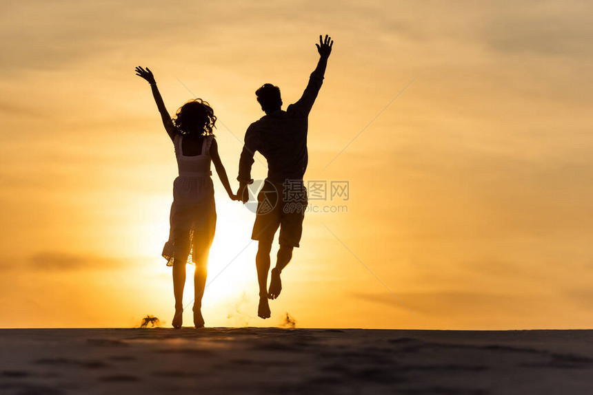 日落时男女在海滩对日晒图片
