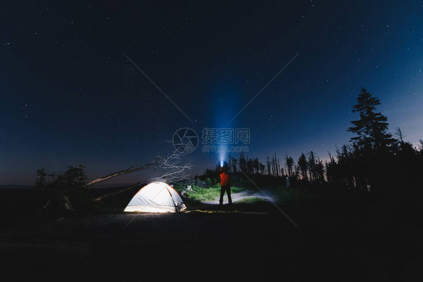 晚上在营地帐篷附近用手电筒的游客图片