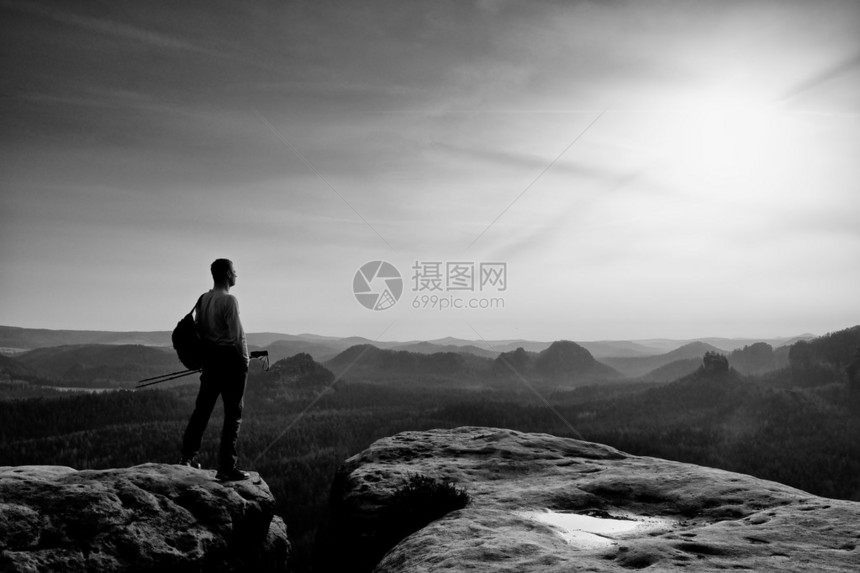 山峰的男子徒步旅行者在秋天有雾的风景的奇妙黎明太阳在地平线之图片