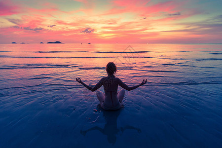 年轻女子在海边做瑜伽在令人惊叹的日图片