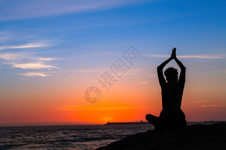 在令人惊叹的日落期间瑜伽冥想的女人图片