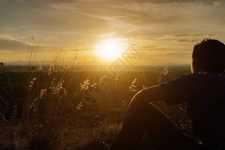 一个孤独的人剪影正在用花草看日落图片