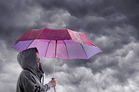 在黑暗的暴风雨天空背景下打着雨伞的女人女人躲在雨伞下避雨保护免受危图片