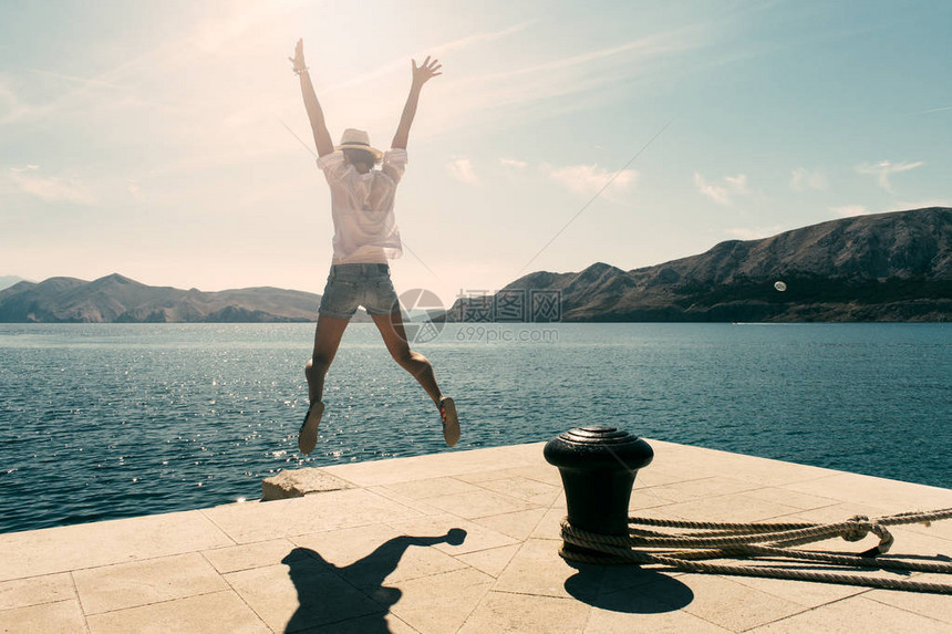 快乐的年轻女子在假期里跳跃日落时无忧图片