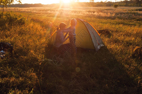 在日落绿草积极生活方式的帐篷中野营图片