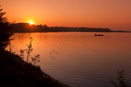 日出时湖上的一艘渔船图片