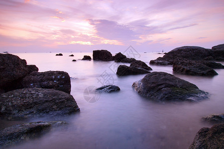 日落时有戏剧波浪和岩石的大海景观图片