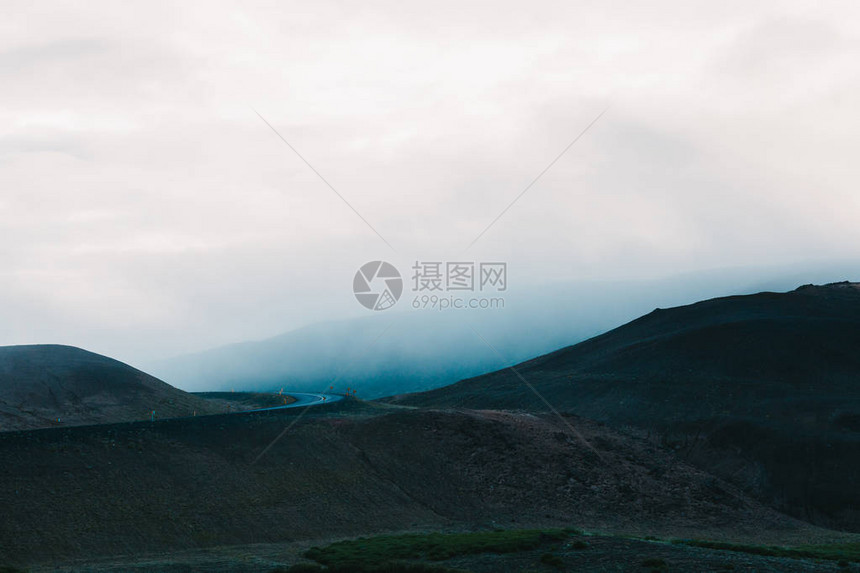 阴天壮丽的冰岛景观山丘和柏油路图片