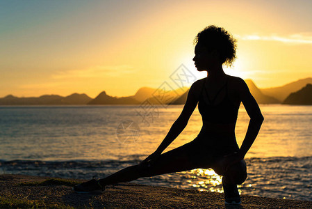 日出时进行伸展运动的健身妇图片