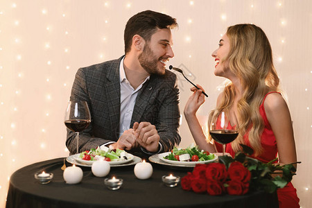 年轻夫妇在餐厅吃浪漫晚饭在餐馆用沙拉和空间喂饱她快乐图片