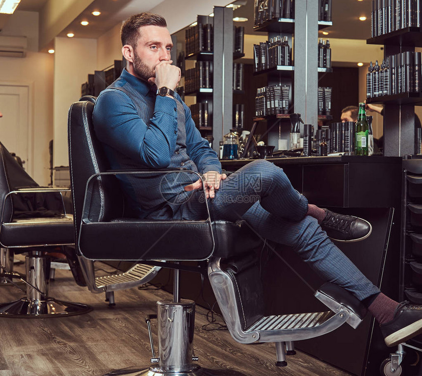 一个专业理发师坐在理发椅上等着下一图片