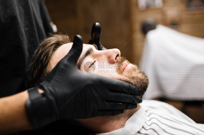 在理发店享受专业面部按摩的男人图片