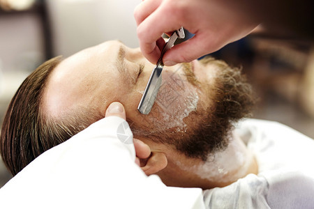 理发店年轻人的理发师剃胡须图片