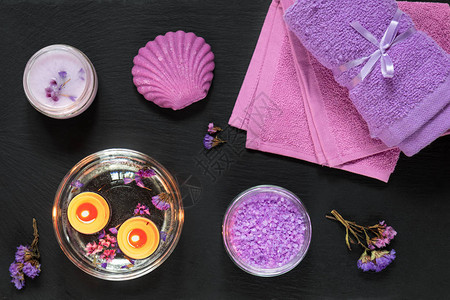 水疗产品薰衣草浴盐干花肥皂化妆霜蜡烛和毛巾紫色的概念平躺在黑色背图片
