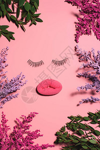 海绵和假眼睫毛被粉色表面的花朵所包围背景图片