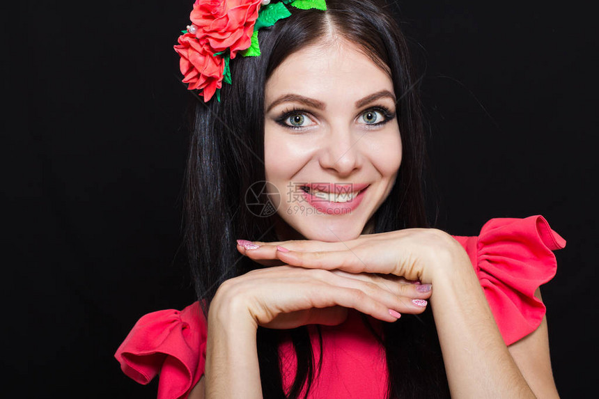 长的黑色头发和深色背景上的红色花朵环的女人微笑着特图片