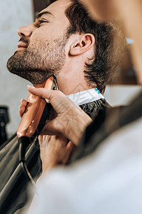 利用电发短和剪胡子对美容沙龙客户进行理发师的近图片