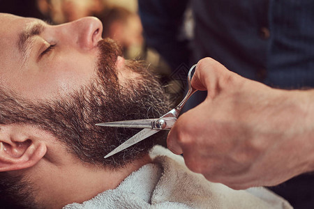 专业理发师在理发店用剪刀和梳子做胡须模特图片