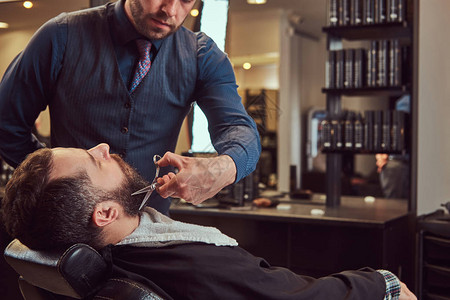 专业理发师在理发店用剪刀和梳子做胡须图片