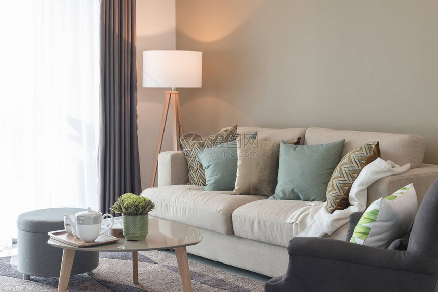 在舒适的沙发和木灯上配有绿色枕头的现代客图片