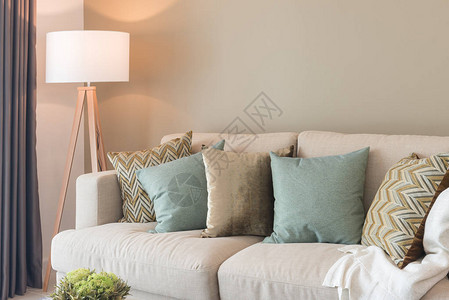 在舒适的沙发和木灯上配有绿色枕头的现代客图片