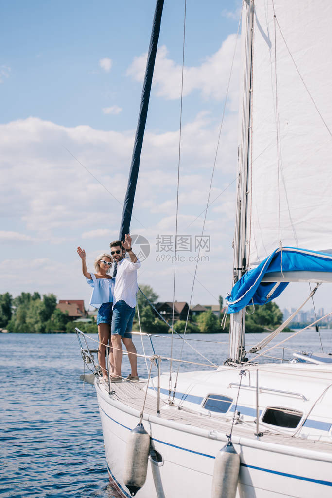 美丽的年轻夫妇在游艇上站在图片