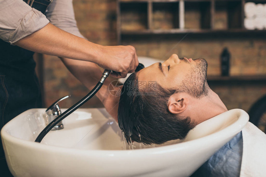 裁剪视图发型师在理发店洗客户头发图片