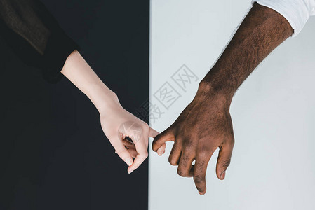 美籍非洲男友和女友在黑白墙附近握着手指的图片